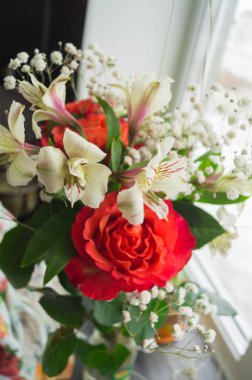 Kırmızı güller ve beyaz Alstroemeria penceresinde