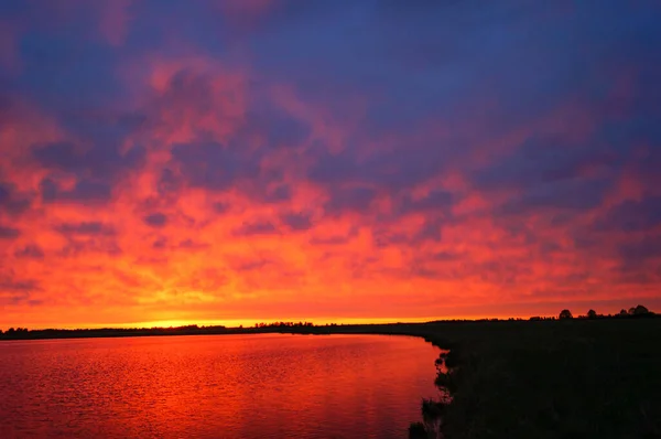 Hermosa puesta de sol roja y rosa sobre el lago en verano — Foto de Stock