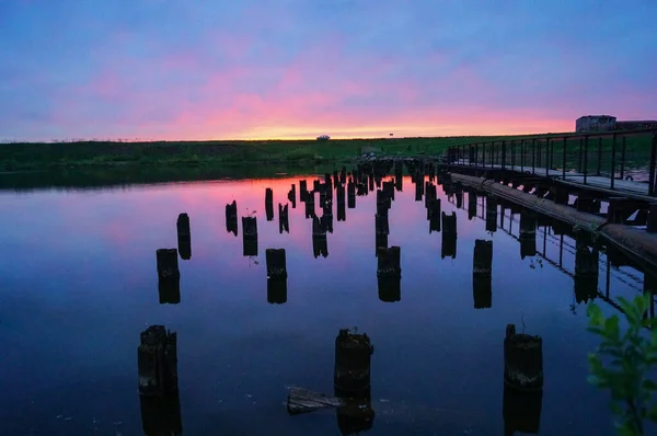 Красивий фіолетово-блакитний захід сонця на невеликих річкових дерев'яних стовпах у воді — стокове фото