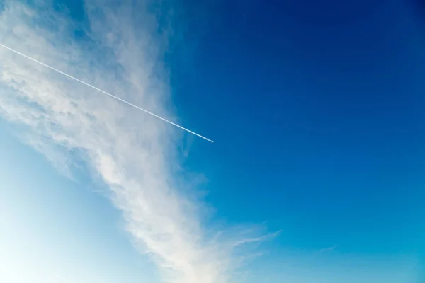 Traço do avião em um céu ensolarado azul — Fotografia de Stock