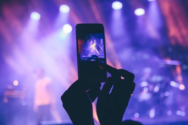 Kadın telefonda bir konserde fotoğraf çeker