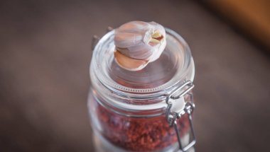 Sarımsak ve baharat ahşap arka plan üzerinde cam kavanozlara 