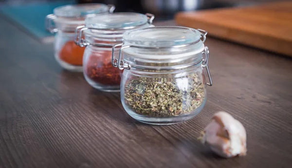 Ajo y especias en frascos de vidrio sobre fondo de madera — Foto de Stock