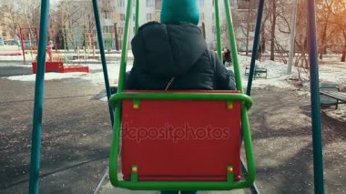 İlkbaharda şehirde bir salıncak üzerinde sallanan kız