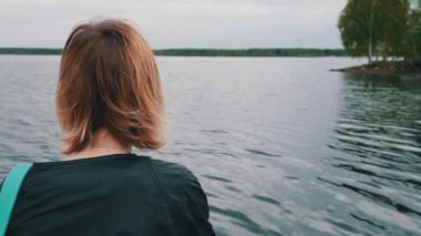 Bir göl kenarında oturan güzel kadın