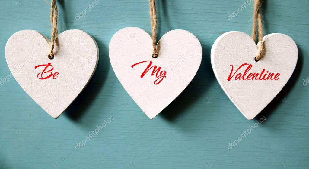 Valentines Day background.Be my Valentine. Decorative white wooden hearts on a blue wooden background.