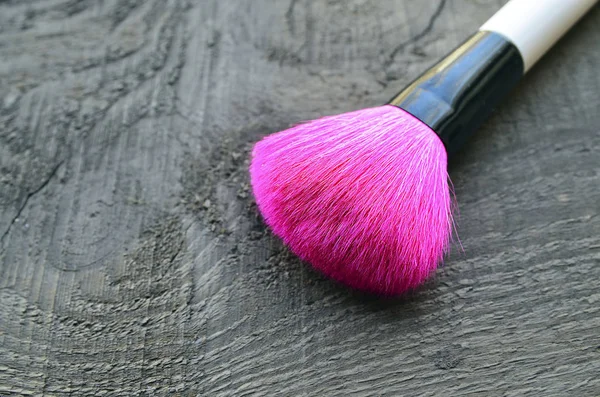Pink makeup brush on old wooden background with copy space.