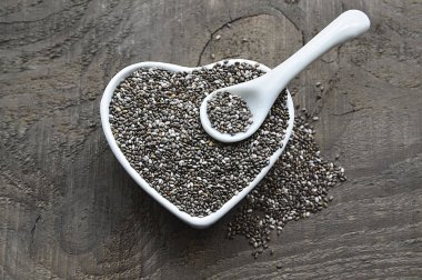 Beyaz kalp içinde Chia tohum eski ahşap arka plan üzerinde kase şeklinde. Ada çayı hispanica tohumları. Sağlıklı gıda veya superfood kavramı.