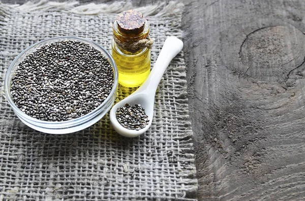 Chia seeds and chia oil on old wooden background.Organic chia seed oil.Salvia hispanica seeds.Healthy food,superfood or bodycare concept.