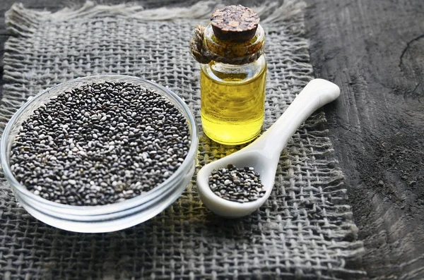Chia seeds and chia oil on old wooden background.Organic chia seed oil.Salvia hispanica seeds.Healthy food,superfood or bodycare concept.