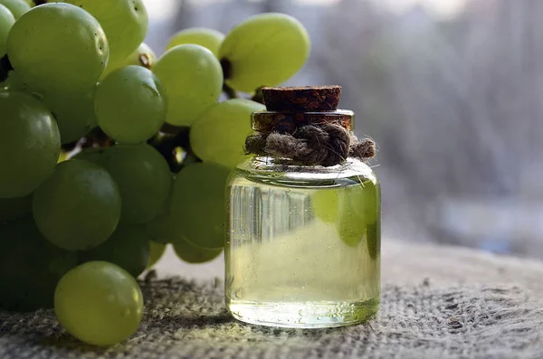 Grape seed oil in a glass jar and fresh grapes on old wooden table.Bottle of organic grape seed oil for spa and bodycare.Spa,Bio,Eco products concept.