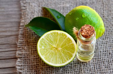 Kireç uçucu yağ taze limon meyve ile cam şişede. Spa, Aromaterapi ve ilgilenmek için limon yağı. Kireç petrol çıkarmak.