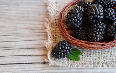 Olgun böğürtlen eski ahşap zemin üzerine çuval bezi kumaş üzerine bir sepet içinde. Blackberry.Healthy yiyecek ya da diyet kavramı.