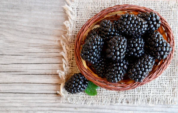 Olgun böğürtlen eski ahşap zemin üzerine çuval bezi kumaş üzerine bir sepet içinde. Blackberry.Healthy yiyecek ya da diyet kavramı.