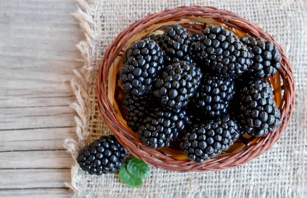 Olgun böğürtlen eski ahşap zemin üzerine çuval bezi kumaş üzerine bir sepet içinde. Blackberry.Healthy yiyecek ya da diyet kavramı.