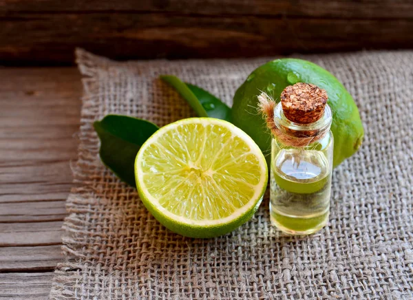 Lime essential oil in a glass bottle with fresh lime fruits.Lime oil for spa, aromatherapy and bodycare.Extract oil of lime . — стоковое фото