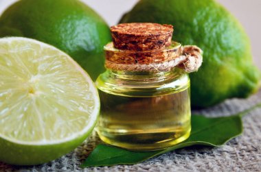 Kireç uçucu yağ taze limon meyve ile cam şişede. Spa, Aromaterapi ve ilgilenmek için limon yağı. Kireç petrol çıkarmak.