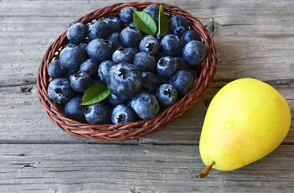 Verse bosbessen en rijpe peer op houten rustieke tafel. Bosbes en peren. Gezond eten, dieet en voeding concept. — Stockfoto