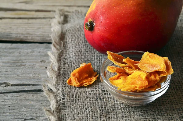 Raw organic dried mango in a glass bowl and fresh ripe mango fruit on wooden rustic table.Dried mangos.