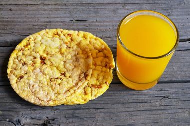 Bütün tahıl crispbreads bardak suyu eski ahşap tablo ile. Kahvaltılık crispbreads. Pirinç ve Mısır crispbreads. Sağlıklı Kahvaltı veya diyet kavramı.