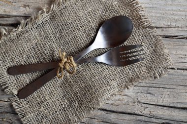 Çatal Bıçak Seti: çatal ve kaşık rustik ahşap masa üzerine çuval bezi kumaş üzerinde. Eski ahşap zemin üzerine çatal bıçak takımı. Arka plan menüsü Restoran için kullanılabilir.