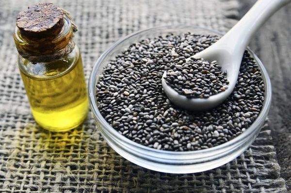 Chia seeds and chia oil on old wooden background.Organic chia seed oil.Salvia hispanica seeds.Healthy food,superfood or bodycare concept.