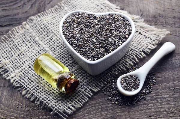 Chia seeds and chia oil on old wooden background.Organic chia seed oil.Salvia hispanica seeds.Healthy food,superfood or bodycare concept.