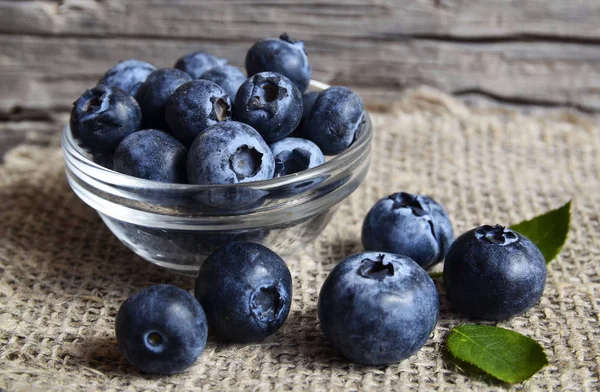 Verse biologische bosbessen in een glazen kom op oude houten achtergrond. Bosbes. Bilberries.Healthy eten, veganistische voeding, dieet en voeding concept. — Stockfoto