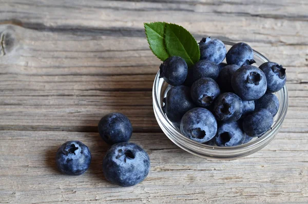 Frische Bio-Blaubeeren in einer Glasschüssel auf altem Holzgrund. bilberries.gesunde ernährung, vegane kost, ernährungs- und ernährungskonzept. — Stockfoto