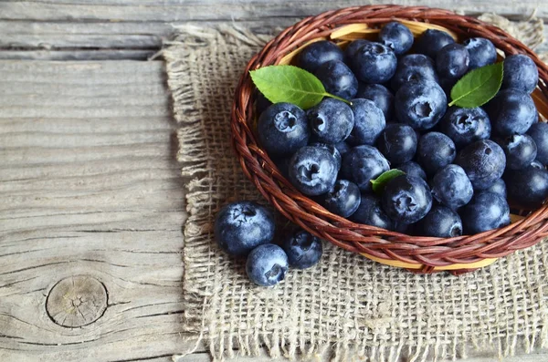 Frisch gepflückte Blaubeeren in einem Korb auf altem Holzboden. Frische Bio-Blaubeere. Bilberries.gesunde Ernährung, vegane Ernährung oder Rohkost-Konzept. Stockbild