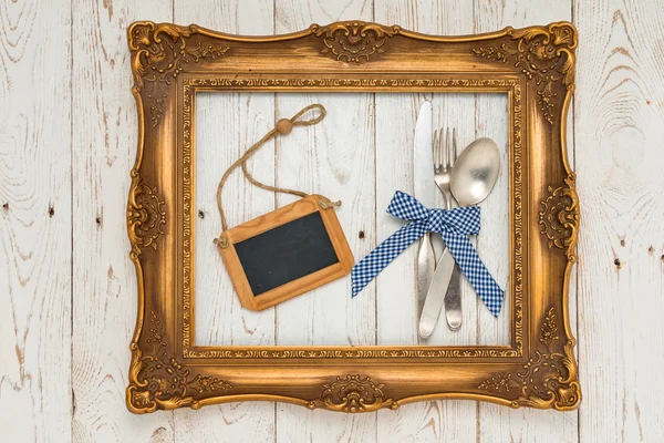 Cutlery in picture frame on wooden table — Stockfoto