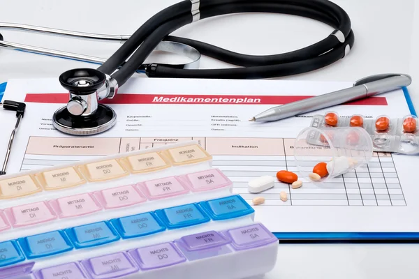 Medicinering plan (på tyska), med tabletter och stetoskop — Stockfoto