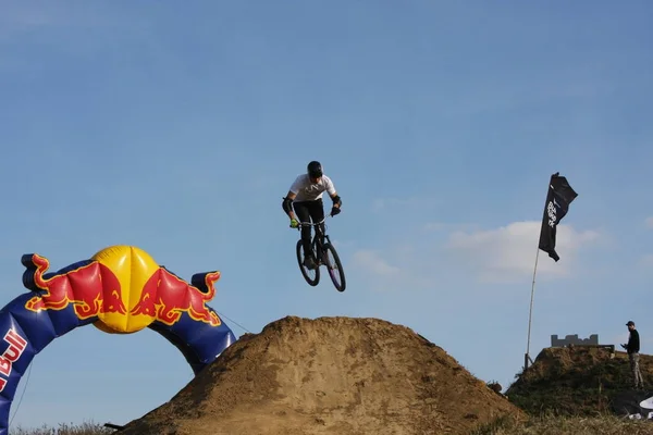 Mann in Sportkleidung springt hoch auf Mountainbike vor Hintergrund der Landschaft — Stockfoto