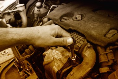 Tamirci araba servisindeki bozuk bir arabayı kontrol ediyor ve tamir ediyor. 