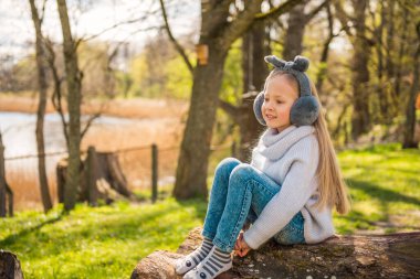 Küçük kız baharda doğada büyük bir kütüğe oturur.