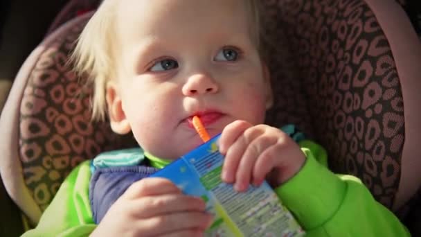 Ett barn dricker från en halm juice närbild — Stockvideo