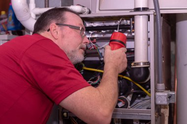 Hvac Tech gaz ocağındaki ocakları kontrol ediyor. 