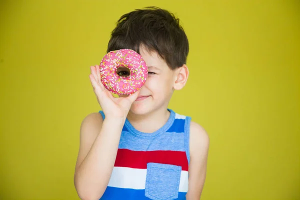 a young boy in a striped t-shirt is about to eat a sweet doughnut