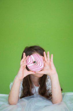 Beyaz elbiseli genç bir kız tatlı bir çörek yiyecek.