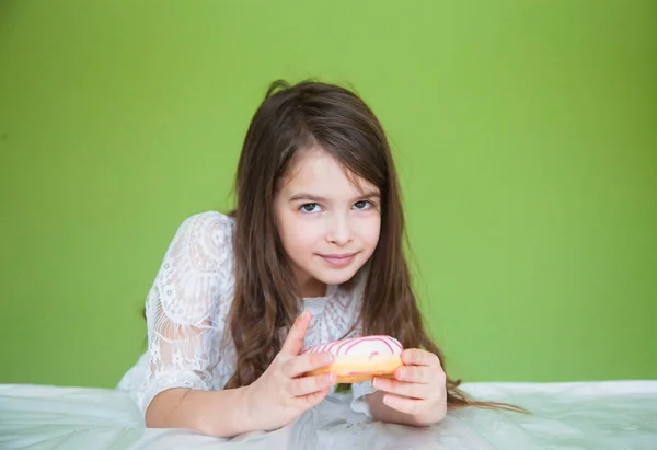 一个穿着白衣的小女孩将要吃甜甜甜圈 — 图库照片