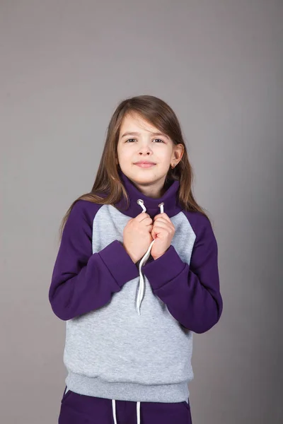 Spor giyimli genç bir kız gri arka planda bunu gösteriyor.