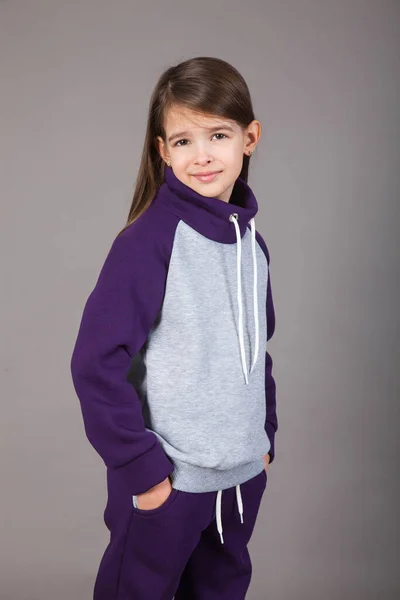 Spor giyimli genç bir kız gri arka planda bunu gösteriyor.