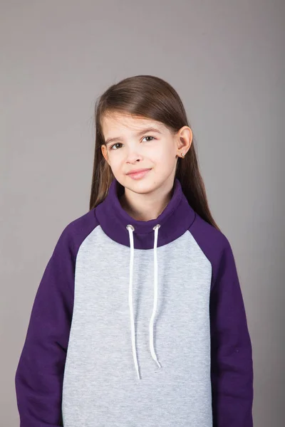 Spor giyimli genç bir kız gri arka planda bunu gösteriyor.