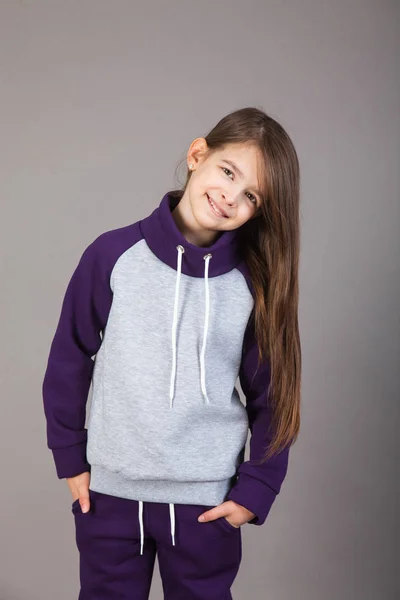 Spor giyimli genç bir kız gri arka planda bunu gösteriyor.