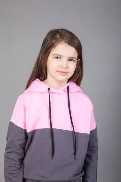 Spor giyimli genç bir kız gri arka planda bunu gösteriyor.