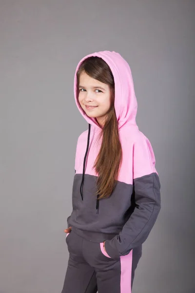 Spor giyimli genç bir kız gri arka planda bunu gösteriyor.