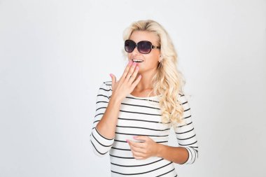 Çizgili elbiseli ve güneş gözlüklü güzel sarışın stüdyoda poz veriyor.
