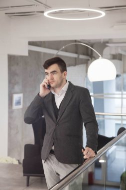Genç ve zeki bir işadamı şık bir takım elbiseyle düşünceli bir şekilde bir ofiste çalışır.