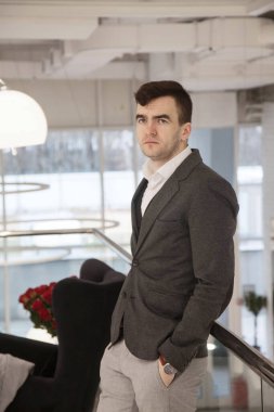 Genç ve zeki bir işadamı şık bir takım elbiseyle düşünceli bir şekilde bir ofiste çalışır.