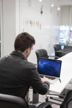 Ofiste dizüstü bilgisayarla çalışan genç ve zeki bir işadamı.